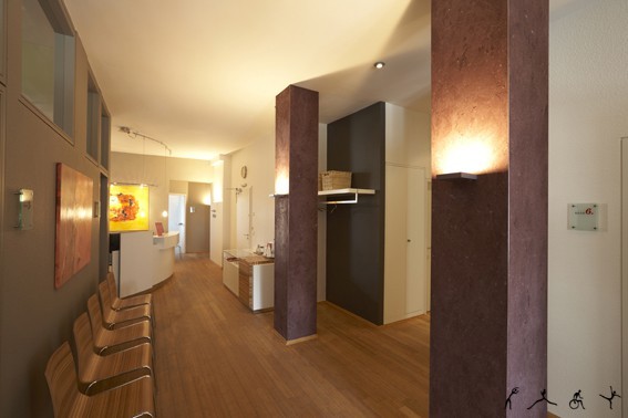 Modernes Wartezimmer einer Arztpraxis mit Holzfußboden, Sitzplätzen und Beleuchtung.