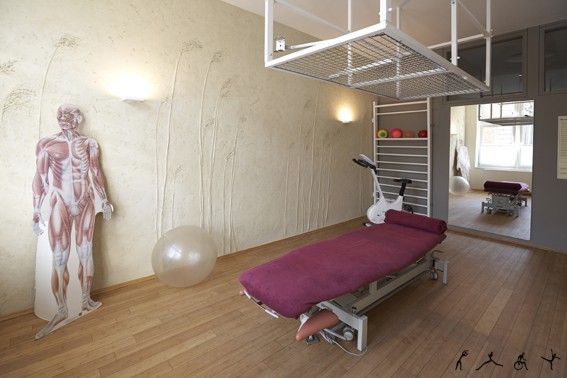 Moderner Physiotherapieraum mit Therapieliege, Skelettmodell und Gymnastikbällen.