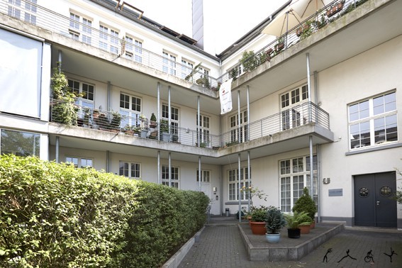 Moderner Innenhof eines barrierefreien Bürogebäudes mit Pflanzen und Balkonen.